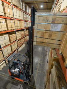 Environmentally friendly electric forklift lifting up a crate in a warehouse.